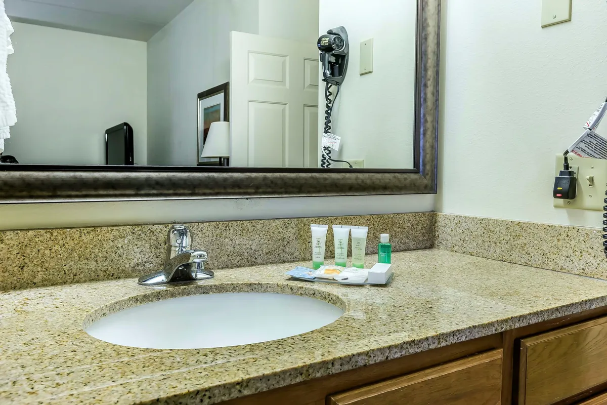 A modern bathroom with a sleek sink and well-lit mirror, complemented by neatly arranged complimentary toiletries and fresh towels. The atmosphere is clean, inviting, and ideal for daily self-care rituals.