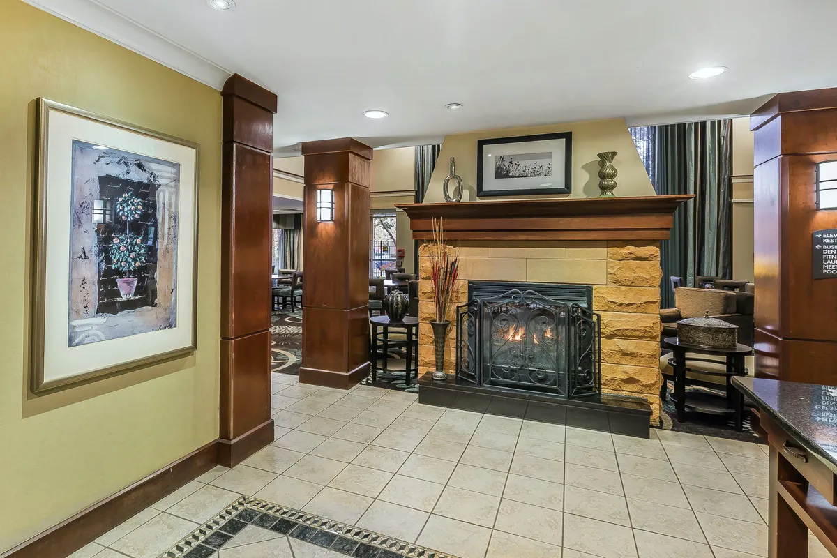 A cozy indoor lounge area with a glowing fireplace, tasteful framed artwork, warm wooden columns, and comfortable seating. The atmosphere is intimate and perfect for unwinding after a day of exploration.