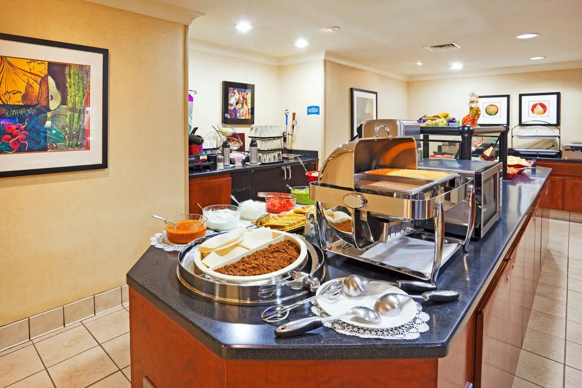 A welcoming buffet counter lined with various food items and decorative artwork, designed for shared breakfasts and relaxed dining. The inviting setting suggests guests gathering to enjoy diverse food choices in a lively communal space.